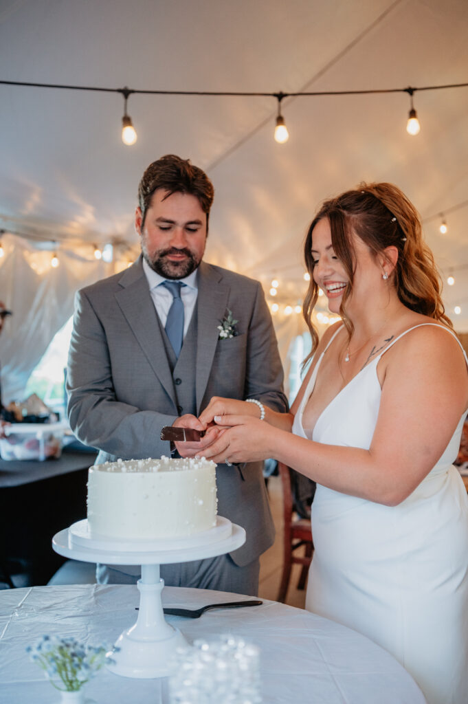 bride and groom cake cutting during tent wedding