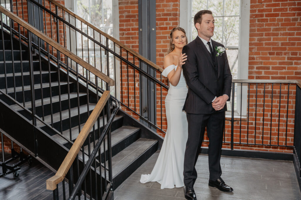 bride and groom first look on staircase at JX Venue