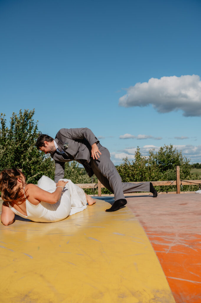 bride and groom falling during playful photos on bounce pad