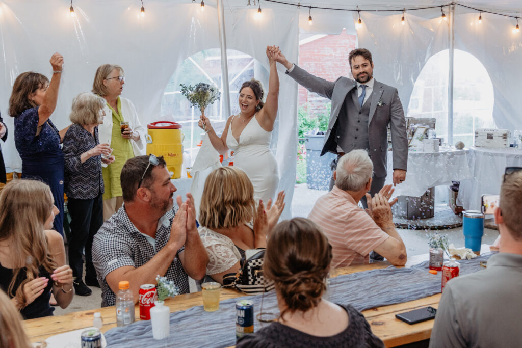 bride and groom grand entrance into reception tent with guests cheering