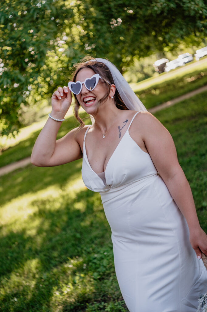 bride laughing with white heart shaped sunglasses