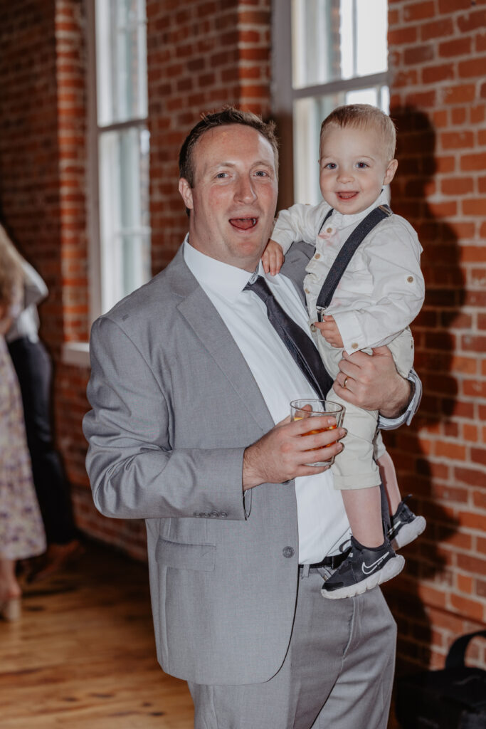 father holding son while both smiling during cocktail hour