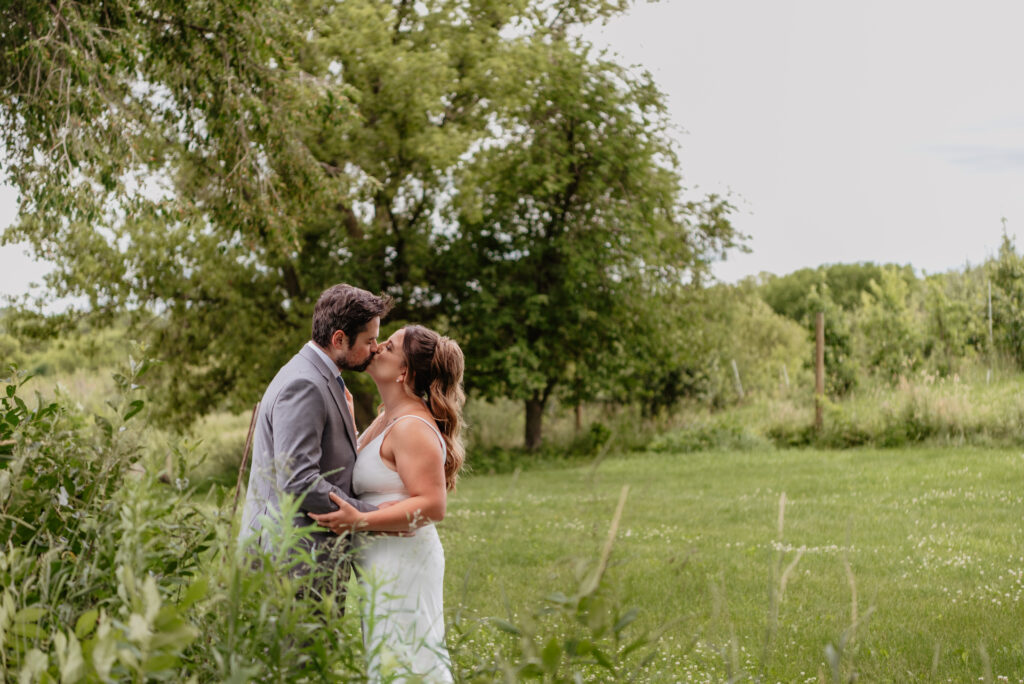 bride and groom kissing amongst grasses at Deer Lake Orchard wedding