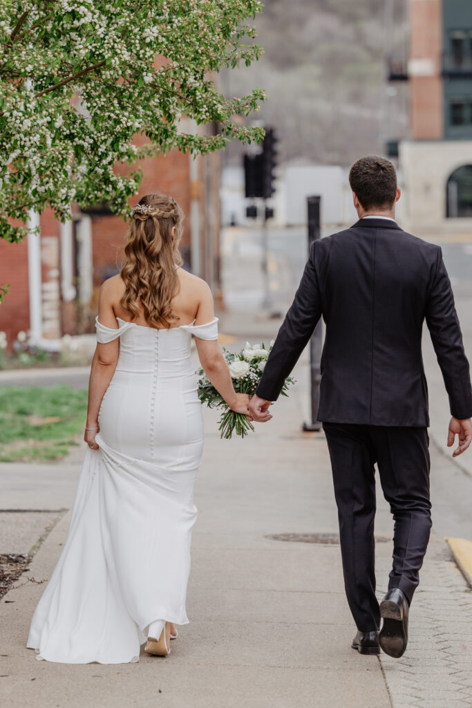 bride and groom walking down sidewalk holding hands