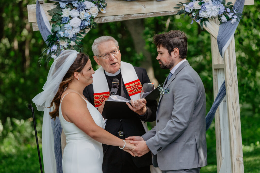 outdoor rustic ceremony site under trees with white aisle runner