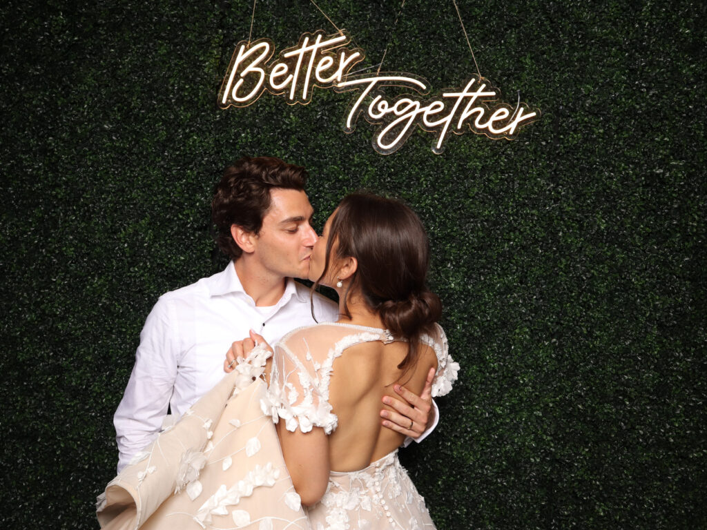 Couple kissing in Photo Booth with neon sign 