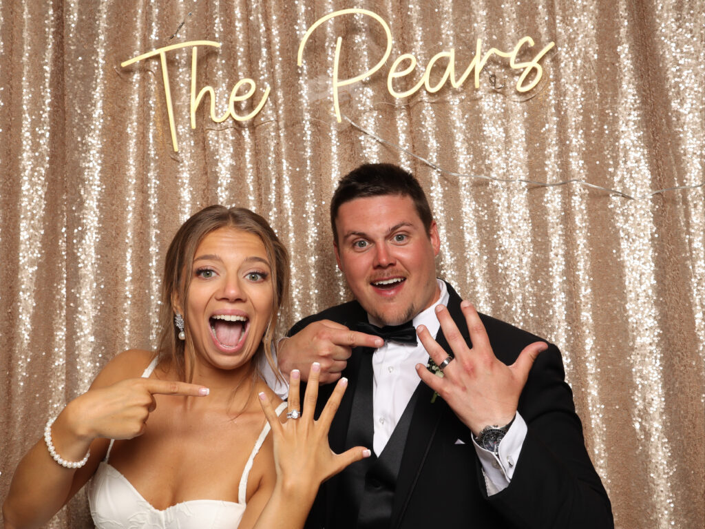 bride and groom in Photo Booth with neon sign
